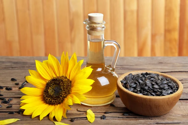 Sunflower with seeds and oil on wooden background — Stock Photo, Image