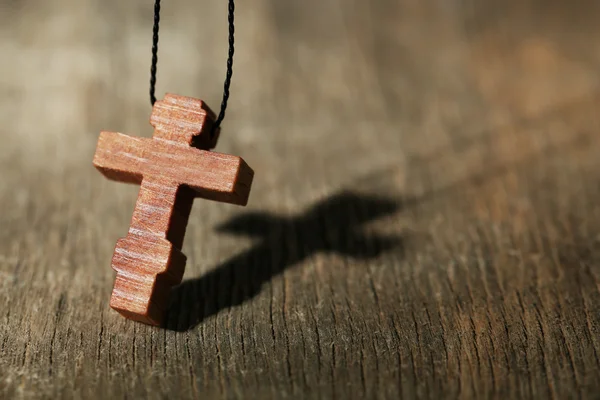 Cruz de madeira com sombra profunda no fundo de madeira — Fotografia de Stock