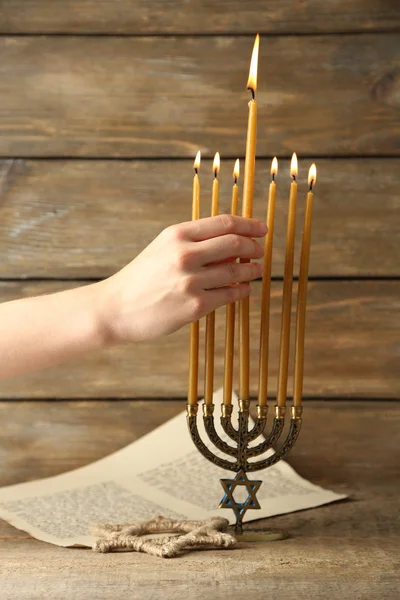 Χέρι κάψιμο των κεριών σε menorah σε ξύλινα φόντο — Φωτογραφία Αρχείου
