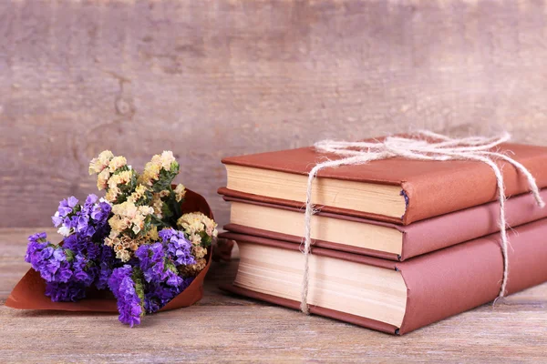 Livros e flores silvestres na mesa de madeira no fundo da parede de madeira — Fotografia de Stock