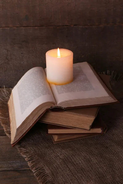 Livros e vela no guardanapo na mesa de madeira no fundo da parede de madeira — Fotografia de Stock
