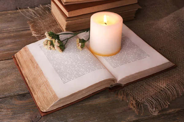 Livres, fleurs et bougies sur serviette sur table en bois sur fond mural en bois — Photo
