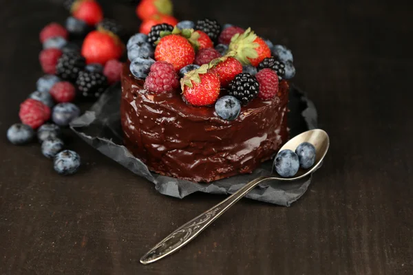 Leckerer Schokoladenkuchen mit verschiedenen Beeren auf Holztisch — Stockfoto