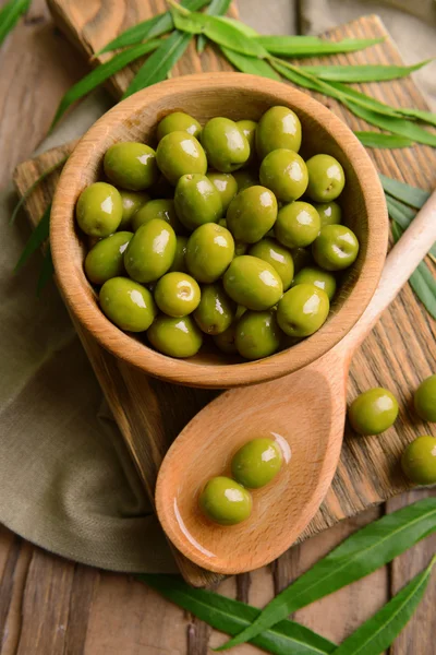 Olive verdi in ciotola con foglie in tavola primo piano — Foto Stock