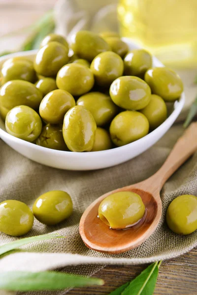 Green olives in bowl with leaves on table close-up — Stock Photo, Image