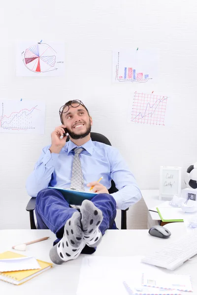 Businessman holding legs on desk — Stock Photo, Image