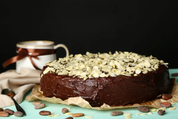 Bolo de chocolate saboroso com amêndoa, na mesa de madeira, no fundo escuro — Fotografia de Stock