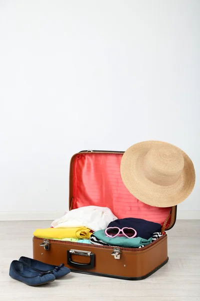 Female clothes in old suitcase on light background — Stock Photo, Image