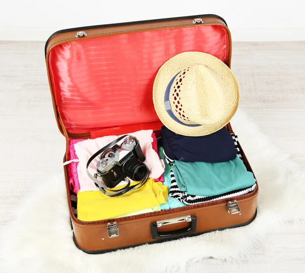 Kobiece ubrania i aparat fotograficzny w starej walizki na jasnym tle — Zdjęcie stockowe