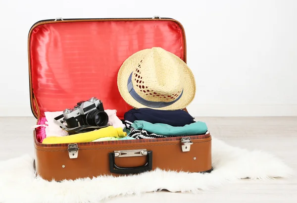 Kvinnliga kläder och fotokamera i gamla resväska på ljus bakgrund — Stockfoto