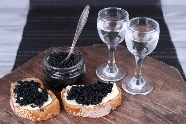 Tereyağı ve siyah havyar, havyar ve koyu arka plan üzerinde ahşap masa üzerinde küçük gözlük Cam Kavanoz ile ekmek dilimleri