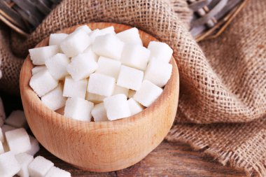 Tablo arka plan üzerinde rafine şeker ahşap kase