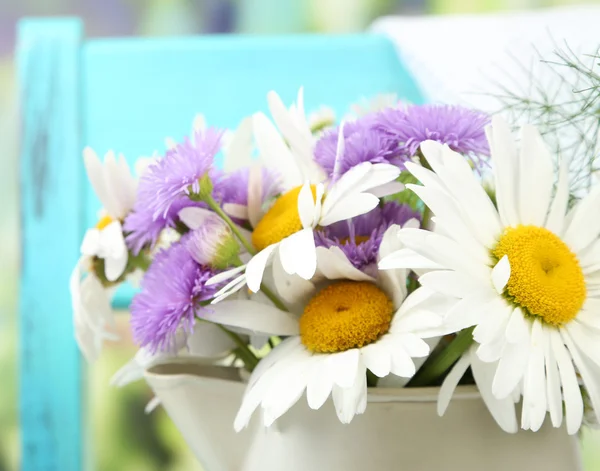 Bouquet of colorful flowers in decorative bucket, on chair, on bright background — Stock Photo, Image