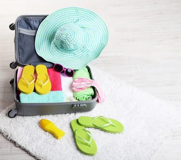 Suitcase with things on white carpet — Stock Photo, Image