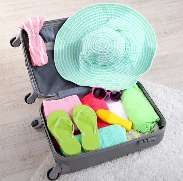 Suitcase with things on white carpet — Stock Photo, Image