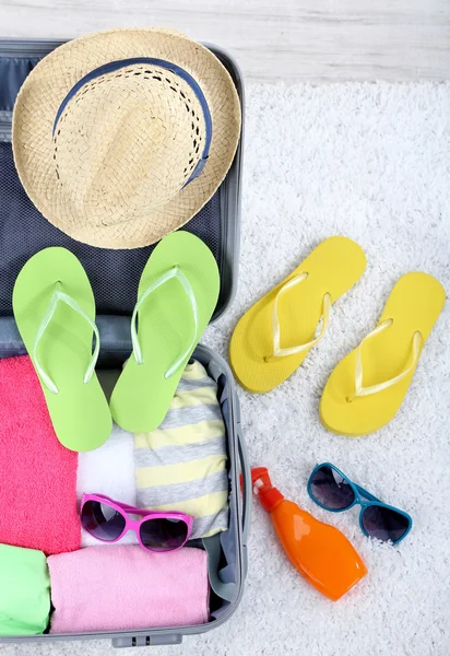 Suitcase with things on white carpet — Stock Photo, Image