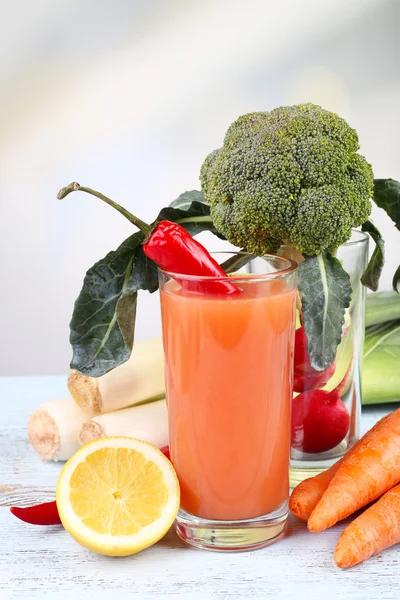 Стакан свежего морковного сока с овощами на деревянном столе — стоковое фото