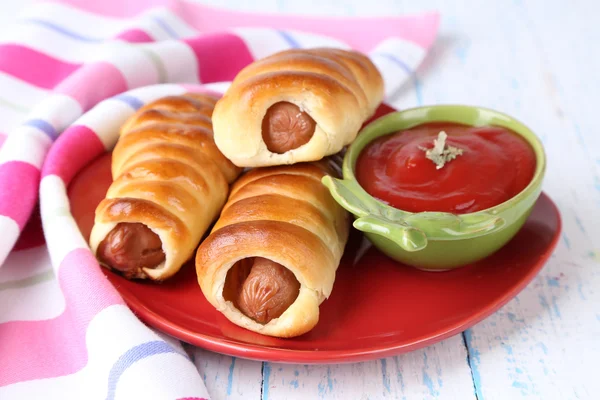 Rollos de salchicha al horno en la placa en primer plano de la mesa —  Fotos de Stock