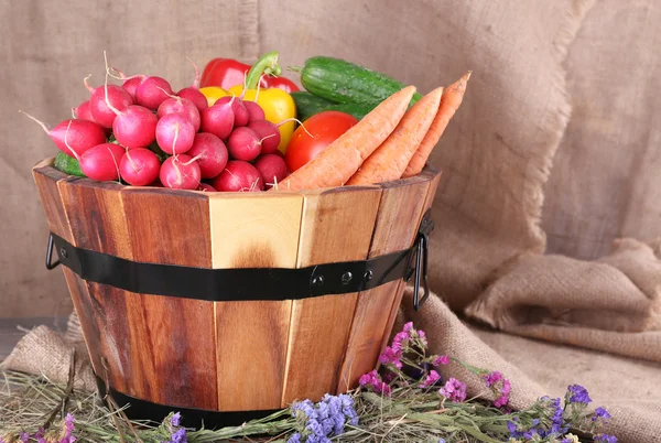 Big round wooden basket with vegetables on sacking background — Stock Photo, Image