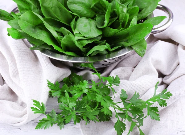 Tuft of fresh sorrel in metal colander on wooden background — Stock Photo, Image