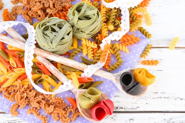 Pasta colorata in cucchiai di legno su fondo di legno — Foto Stock