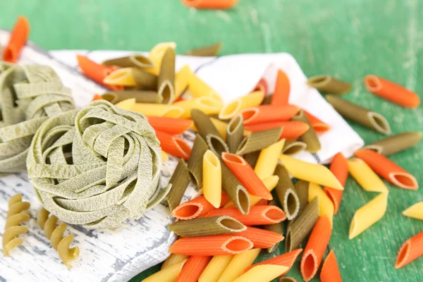 Pasta colorata in cucchiai di legno su fondo di legno — Foto Stock