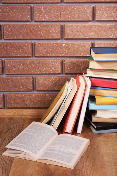 Buku-buku di meja kayu pada latar belakang dinding bata — Stok Foto