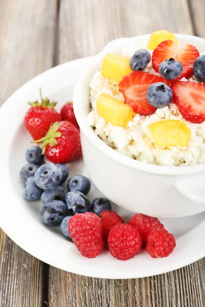 Cottage cheese with fruits and berries in bowl on wooden table — Stock Photo, Image