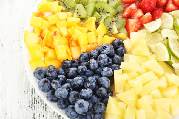 Frutas fatiadas no prato na mesa de madeira — Fotografia de Stock