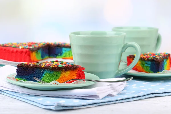 Delicious rainbow cake on plate, on table, on light background — Stock Photo, Image