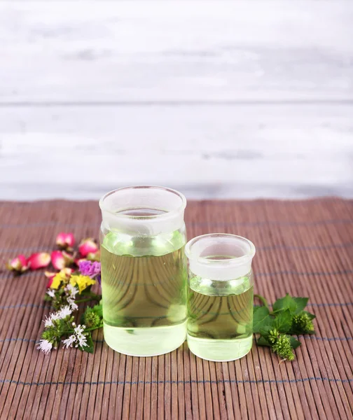 Essential oil with different medicine plants, on wooden background — Stock Photo, Image