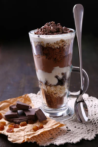 Yogurt, with chocolate cream, chopped chocolate and muesli served in glass on wooden background — Stock Photo, Image