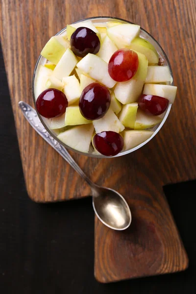 Petit déjeuner sain - yaourt au raisin frais et tranches de pomme et muesli servi dans un bol en verre, sur fond de bois — Photo