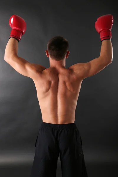 Guapo joven deportista muscular con guantes de boxeo sobre fondo oscuro — Foto de Stock