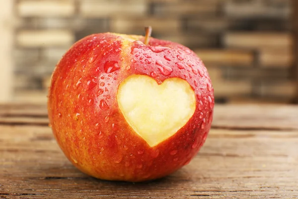 Punainen omena sydän puinen pöytä, lähikuva — kuvapankkivalokuva