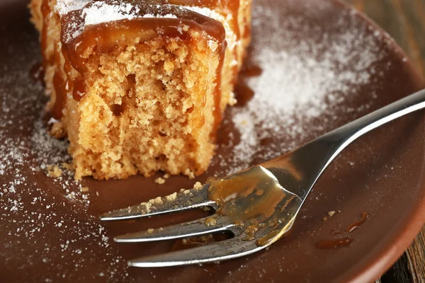 Pièce de gâteau délicieux à moitié mangé sur une table en bois — Photo