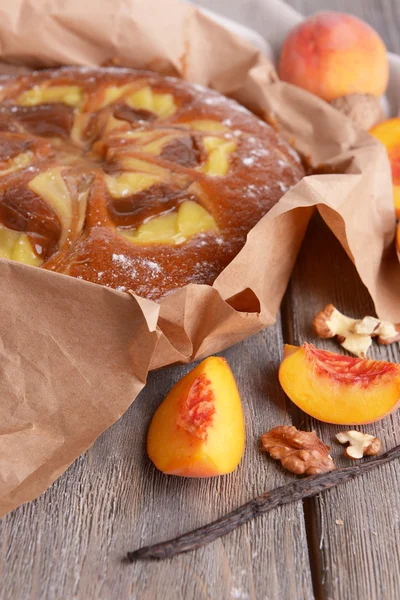 Delicious cake with peach and nuts on wooden table close up — Stock Photo, Image