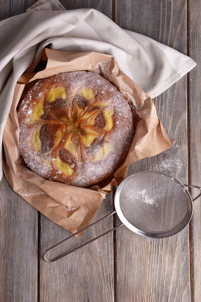 Delicious cake and sieve with powdered sugar on wooden table — Stock Photo, Image