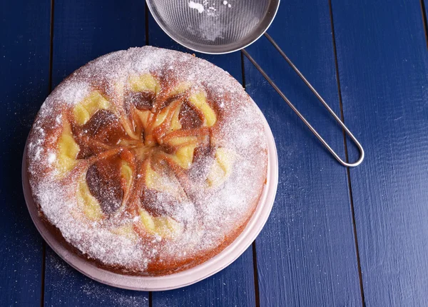 Delicious cake and sieve with powdered sugar on wooden table — Stock Photo, Image