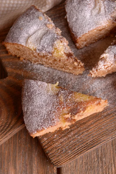 Trozos de delicioso pastel en la tabla de cortar en la mesa de madera — Foto de Stock