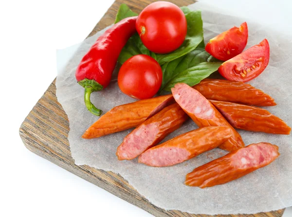 Salsichas finas e legumes defumados em tábua de corte, isolados em branco — Fotografia de Stock