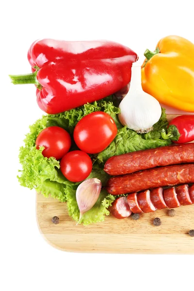 Smoked thin sausages and vegetables on cutting board, isolated on white — Stock Photo, Image
