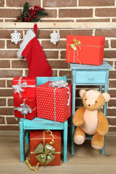 Presentes de Natal na cadeira no fundo da parede de tijolo marrom — Fotografia de Stock