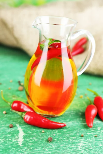 Homemade natural infused olive oil with red chili peppers on color wooden background — Stock Photo, Image