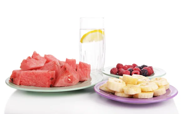 Rebanadas de frutas y bayas en el plato con un vaso de agua aislado en blanco —  Fotos de Stock