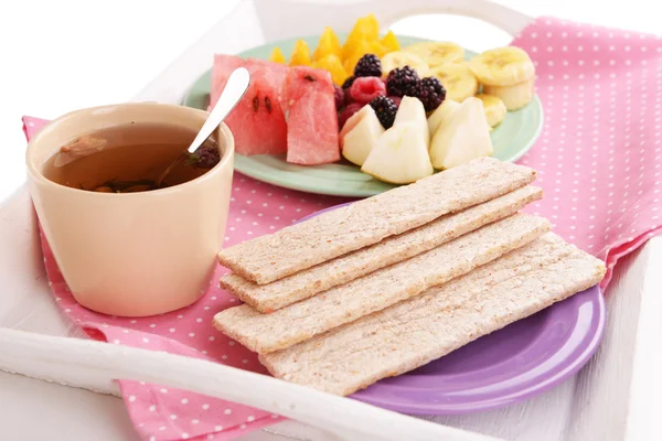 Slices of fruits with crispbreads on plate and cup of tea on wooden tray close up — Stock Photo, Image