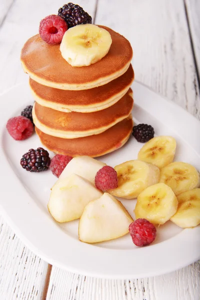Pannenkoek met fruit en bessen op plaat op houten tafel — Stockfoto