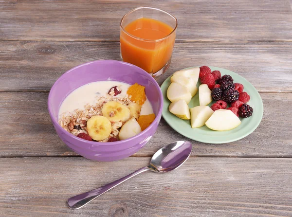 Slices of fruits with berries and muesli on wooden table — Stock Photo, Image