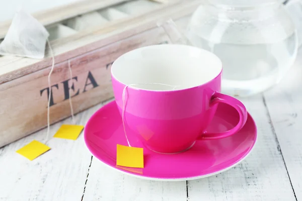 Cup and teapot with tea bags on wooden table close-up — Stock Photo, Image