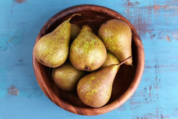 Ripe pears in bowl, on color wooden background — Stock Photo, Image